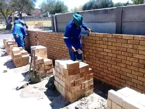 Two bricklayers building a face brick wall