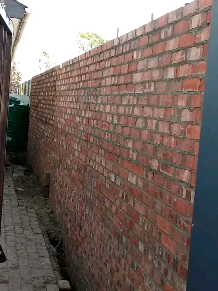 Long face brick boundary wall running down a property