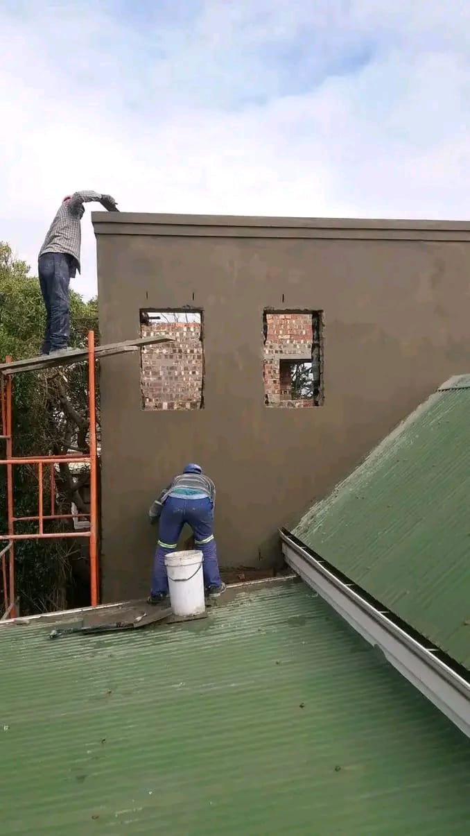 Team plastering an exterior wall from scaffolding